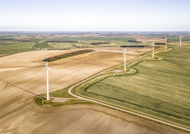 Free photo aerial shot of the turbines on the beautiful green fields near the plowed farms