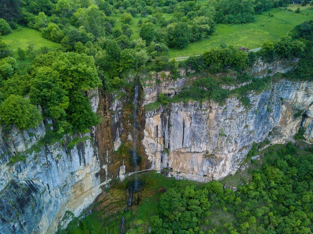 Aerial shot of a waterfall on the beautiful mountain covered with trees