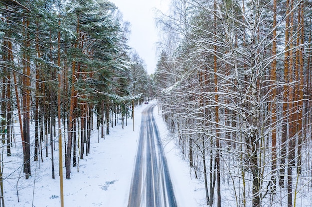 Free photo aerial shot of winter road through the forest