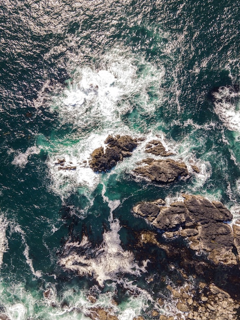 Free photo aerial vertical shot of a sea with rocky stones