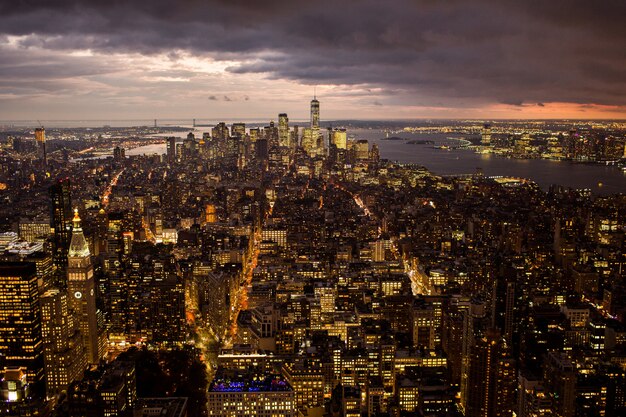 Aerial view of a beautiful cityscape with illuminated buildings and a sea under the storm clouds