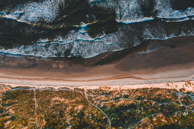 Aerial view of the beautiful coastline with ocean waves crashing into the sandy beaches