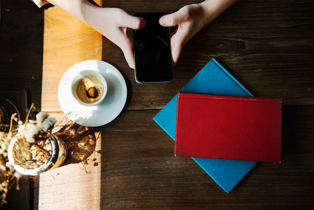 Free Photo aerial view closeup of hands with mobile phone in coffee cafe on wooden table