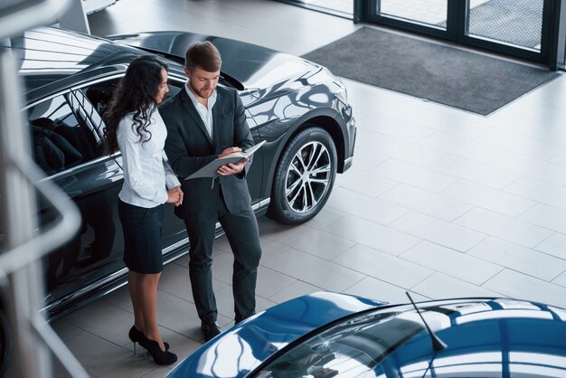 Aerial view. Female customer and modern stylish bearded businessman in the automobile saloon