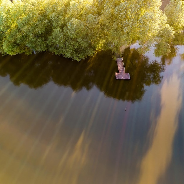 Free photo aerial view of the lake with wooden bridge for fishing surrounded by forest photo by drone