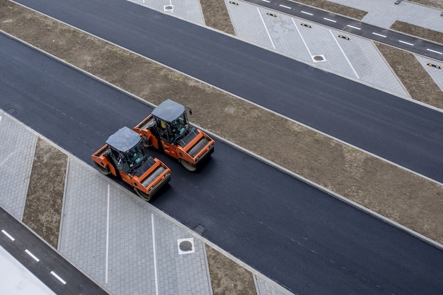 Free Photo aerial view of orange vibratory asphalt roller compactor on a new pavement