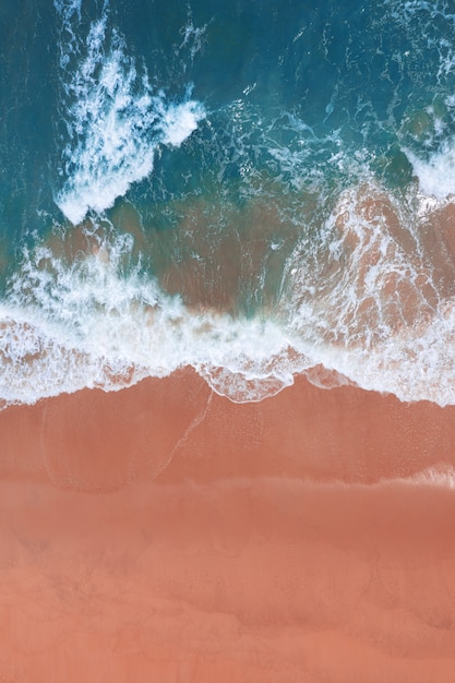 Free photo aerial view of pink beach and blue ocean wave.