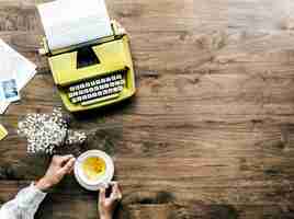 Free photo aerial view of retro typewriter and a woman with a cup of tea