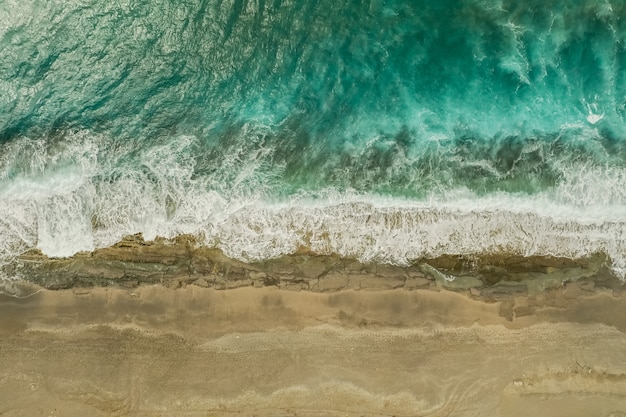 Aerial view of sand meeting the sea water and waves