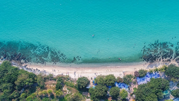 Aerial view of sandy beach with tourists swimming.