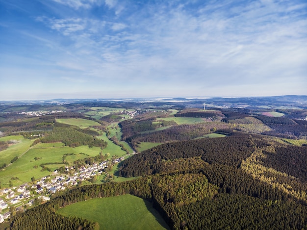 Aerial view shot of beautiful green fields and houses of the countryside on a sunny day