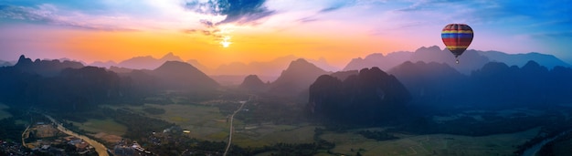 Aerial view of Vang vieng with mountains and balloon at sunset.