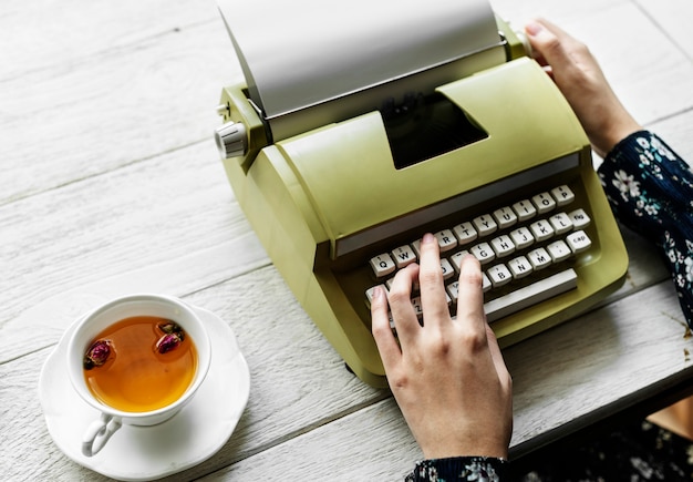 Aerial view of a woman typing on a retro typewriter blank paper