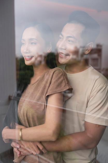 Free photo affectionate couple embracing and looking through the window at home