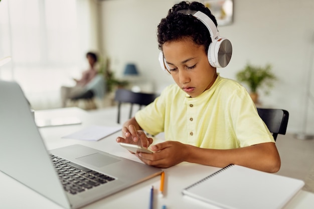 African American boy using smart phone while learning at home