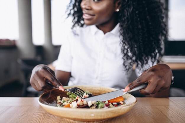 African american business woman eating salad in a cafe close up