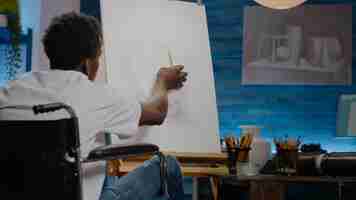 Free photo african american disabled young artist drawing vase on canvas