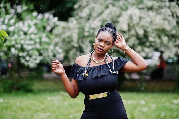 African american doctor female at black dress with stethoscope posed outdoor under rain