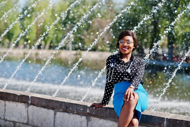 African american doctor female with stethoscope posed outdoor background fountains