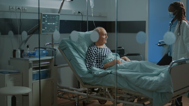 African american doctor fixing adjustable bed in hospital ward