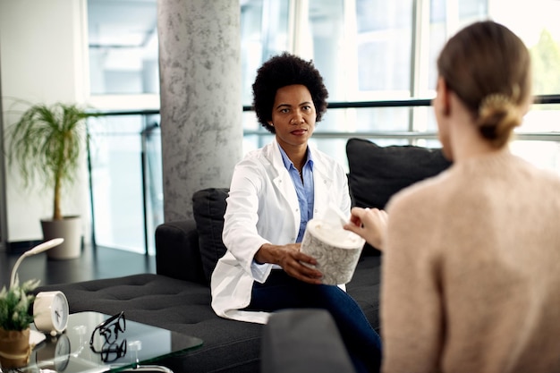 African American doctor offering tissue to a patient during therapeutic session