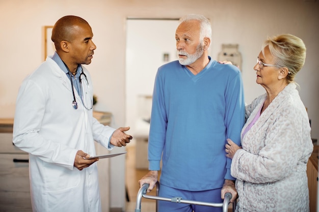 Free photo african american doctor talking to elderly couple at nursing home