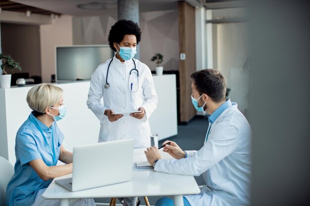 African American doctor talking to her colleagues while working at medical clinic during coronavirus pandemic