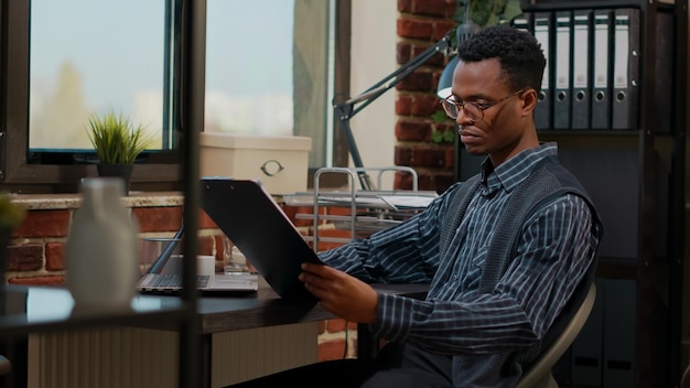 African american employee analyzing e shopping report on laptop at workplace. Business consultant planning financial statistics to create commercial development and company growth.