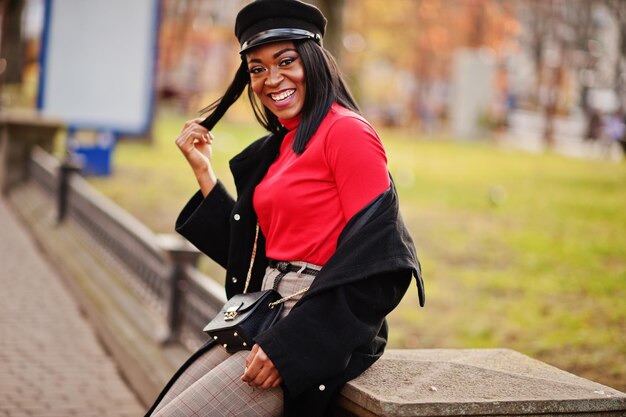 African american fashion girl in coat and newsboy cap posed at street