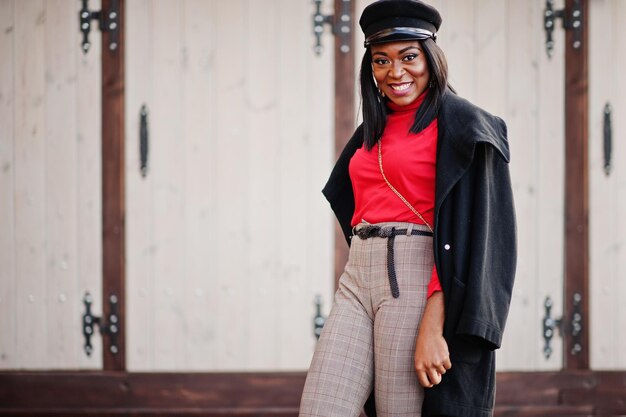 African american fashion girl in coat and newsboy cap posed at street