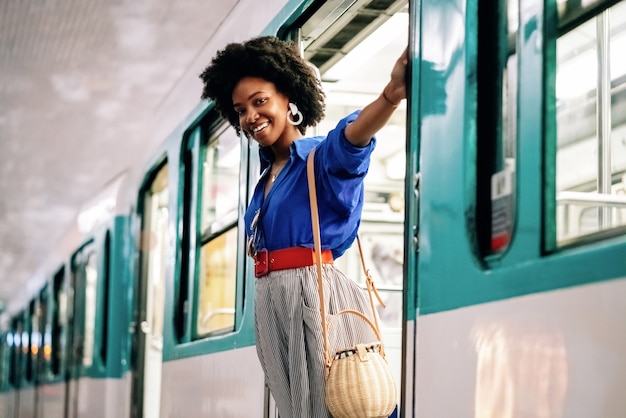 African American female hanging on a train door