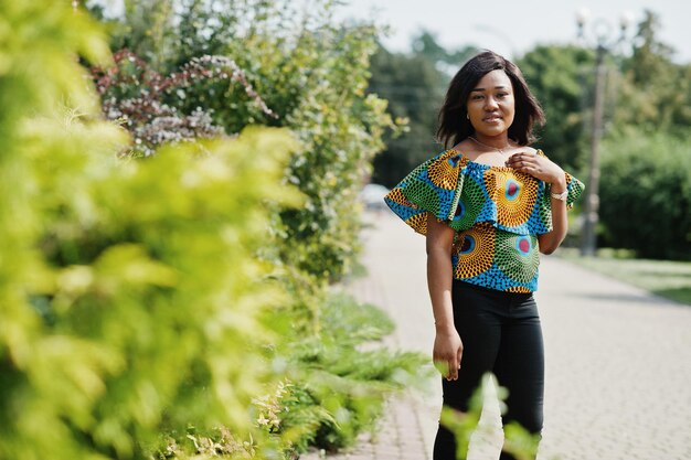 African american girl in coloured shirt and black pants posed outdoor Fashionable black woman