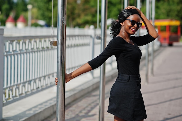 African american girl in sunglasses black clothes and shirt posed outdoor Fashionable black woman