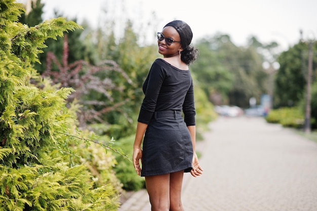 African american girl in sunglasses black clothes and shirt posed outdoor Fashionable black woman