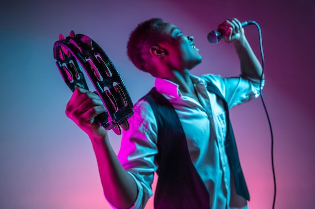 African American handsome jazz musician playing tambourine and singing.