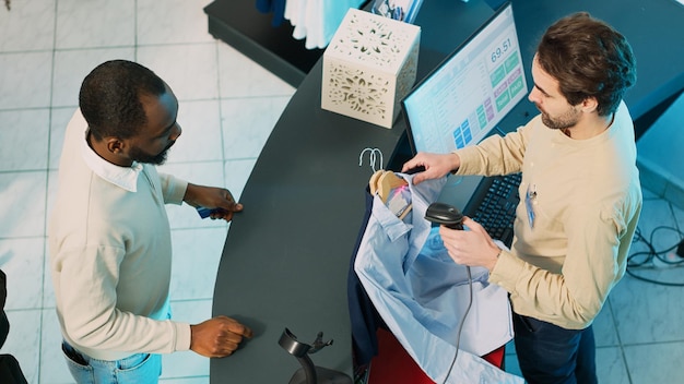 Free photo african american man buying clothes at shop cash register, using card to make transaction on pos terminal. store employee giving shopping bags to customer, commercial activity. handheld shot.