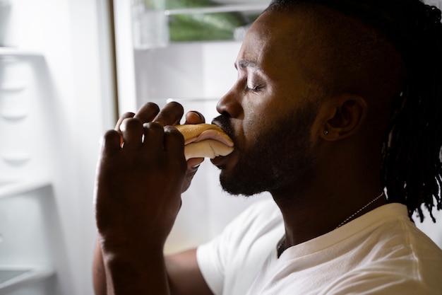 African american man eating from the fridge at night