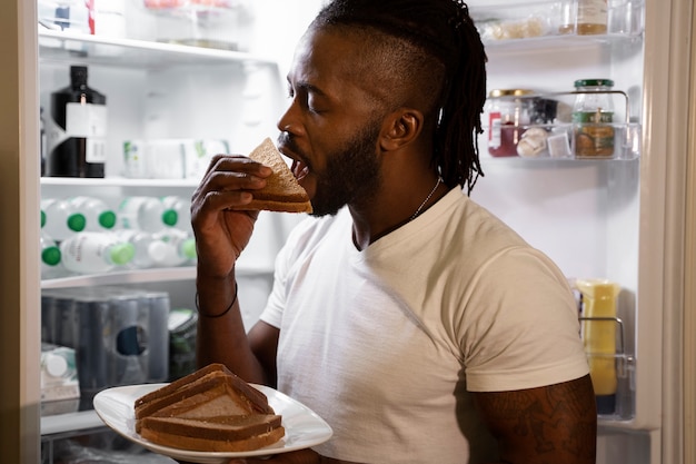 African american man eating from the fridge at night