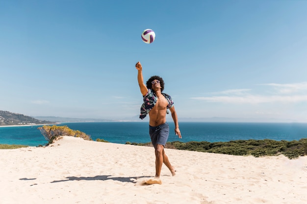 Free Photo african american man playing with ball on beach