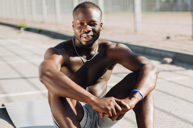 African American man sits tired on the ground after doing his exercises