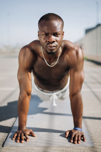 African American man stands on his arms on the ground doing push-ups 