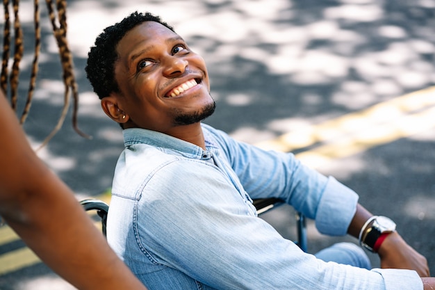 An african american man in a wheelchair enjoying a walk outdoors with his girlfriend