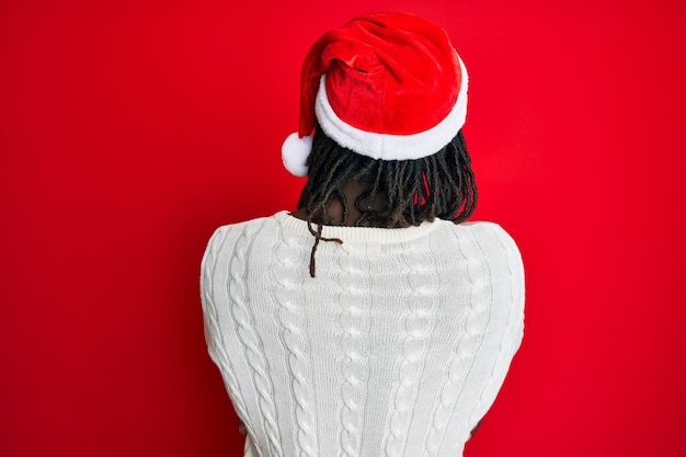 Free photo african american man with braids wearing christmas hat standing backwards looking away with crossed arms