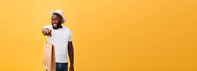 African american man with colorful paper bags isolated on yellow background