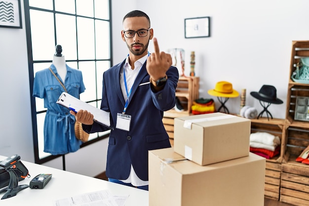 African american man working as manager at retail boutique showing middle finger impolite and rude fuck off expression