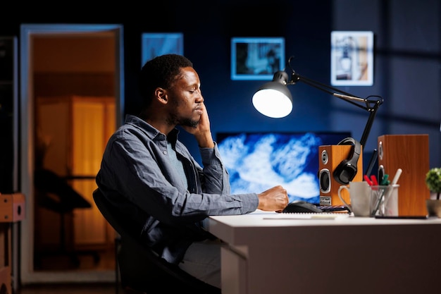 African american man yawning while doing remote work