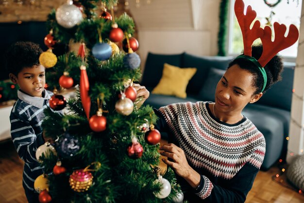 African American mother and son decorating Christmas tree at home