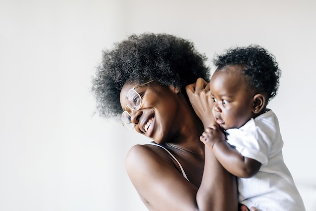 African-American mother taking care and loving her baby against a white background