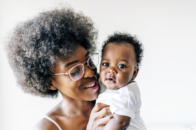 African-American mother taking care and loving her baby against a white surface