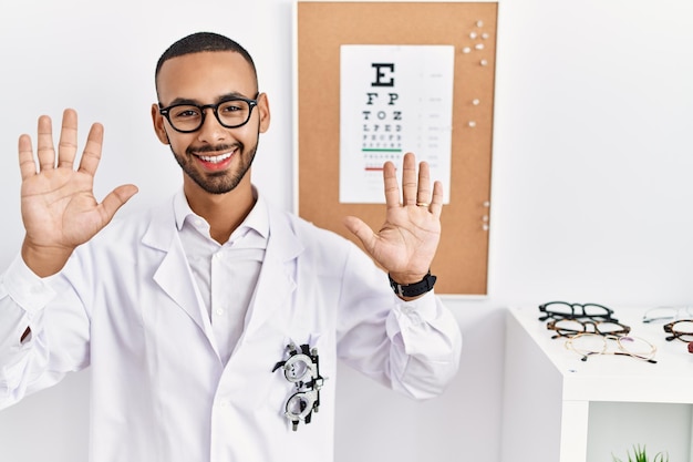 Free Photo african american optician man standing by eyesight test showing and pointing up with fingers number ten while smiling confident and happy.